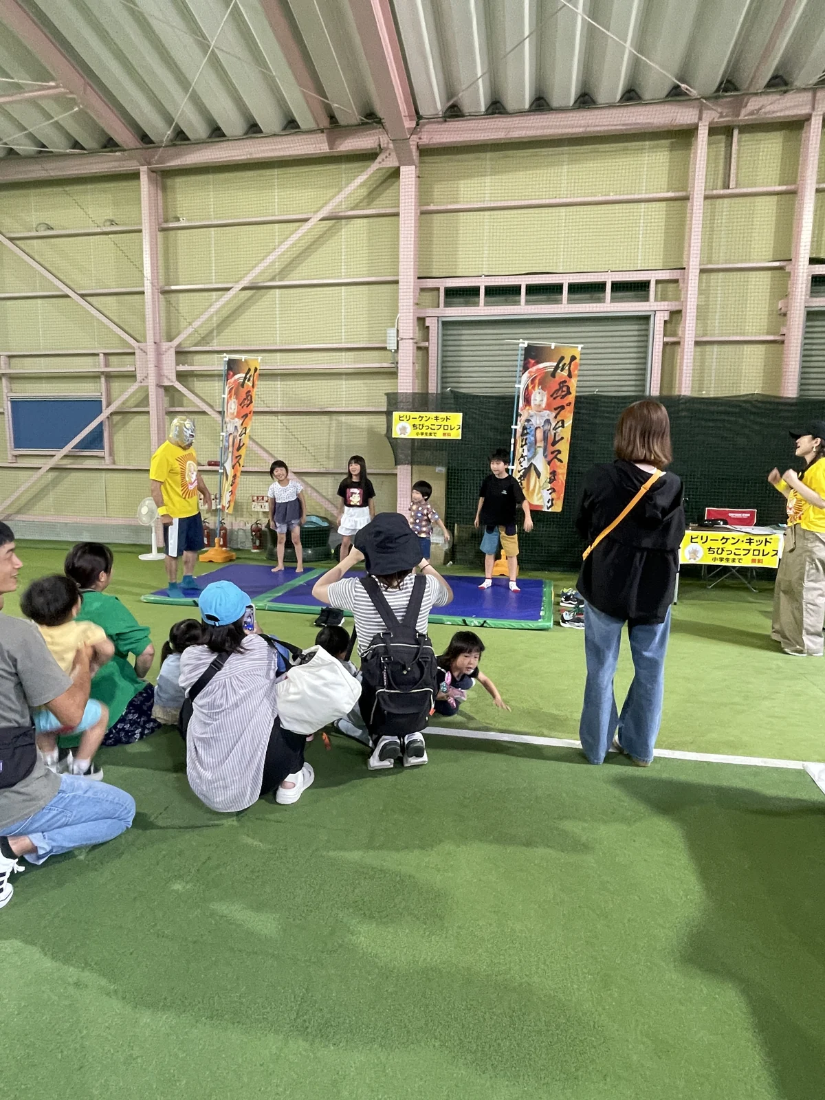 室内コートのマットでちびっこプロレスを体験する子どもたち